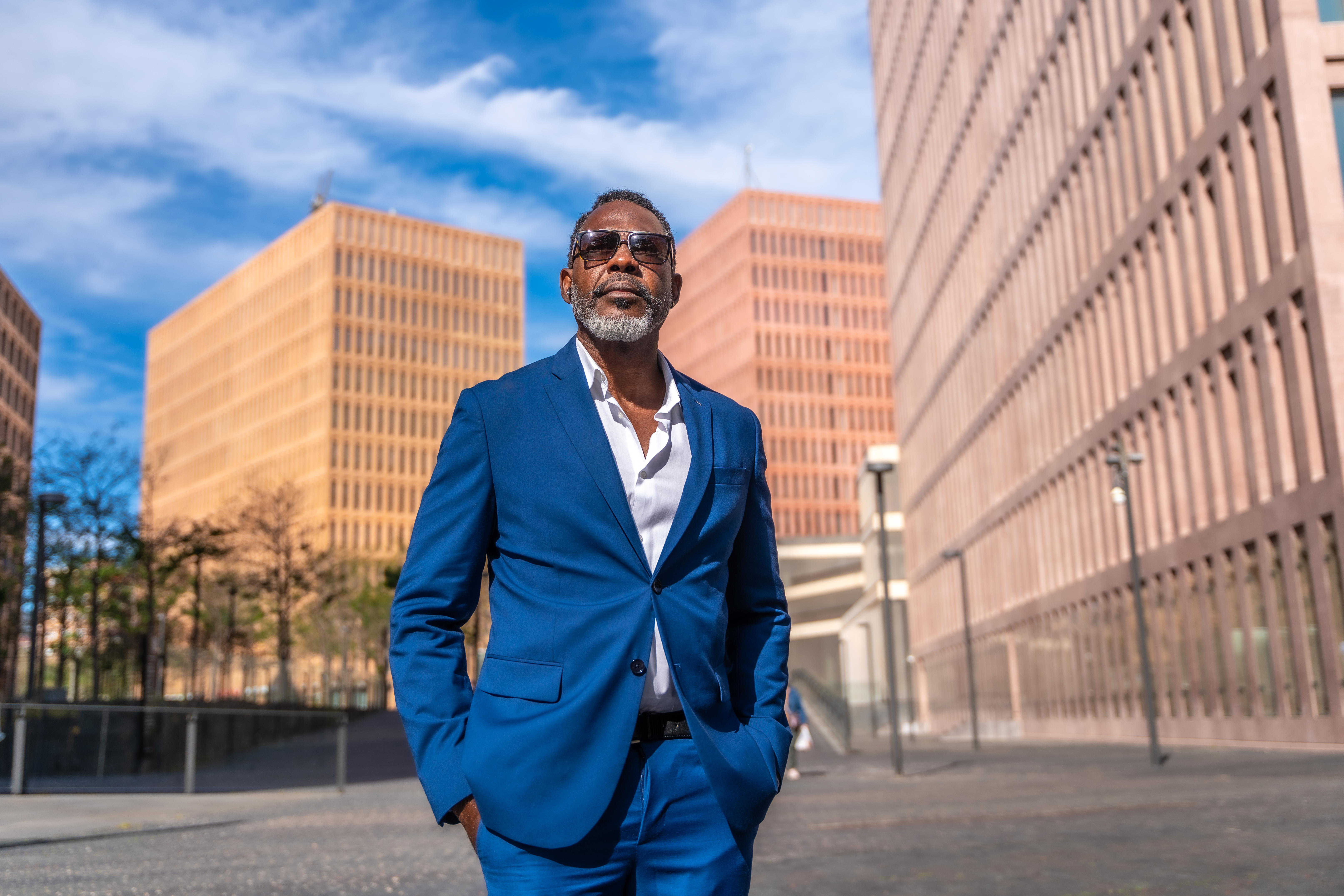 Cool african mature businessman in sunglasses and suit walking along the street
